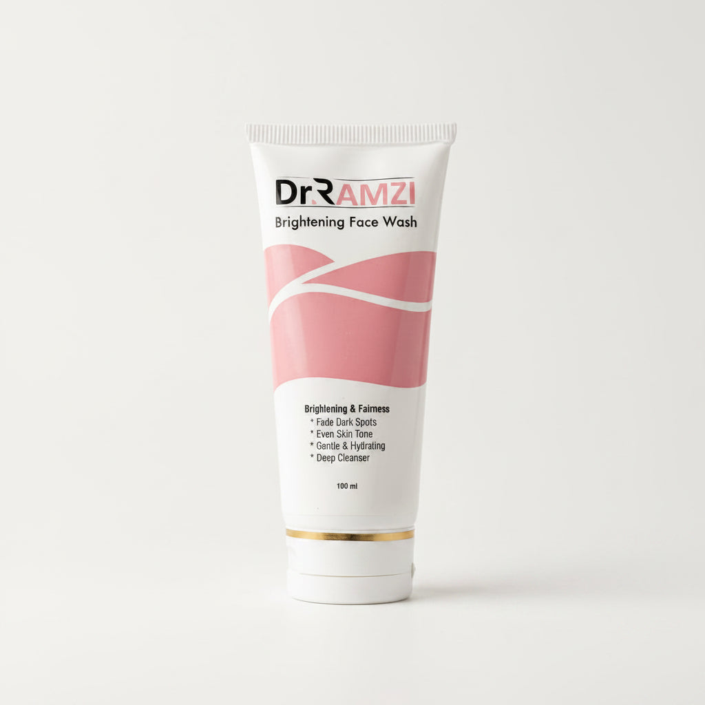 A 100 ml squeeze tube of Dr RAMZI Brightening Face Wash, featuring a white and pink design with a gold accent band near the cap, set against a plain light gray background.
