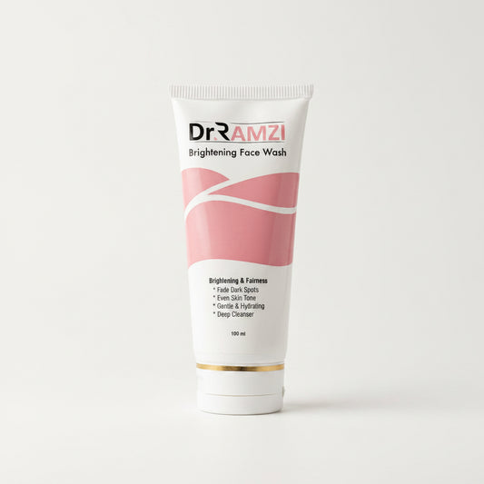 A 100 ml squeeze tube of Dr RAMZI Brightening Face Wash, featuring a white and pink design with a gold accent band near the cap, set against a plain light gray background.